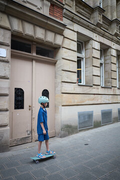 Young child skateboarding in urban setting wearing safety gear and stylish outfit