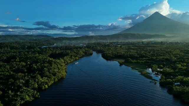 Aerial river leading to Mayon Volcano at sunrise with boat wake in Albay, Philippines. Ideal for travel and Southeast Asia destination content.