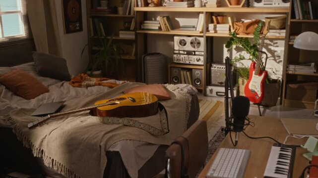 Acoustic guitar resting on bed in empty home recording studio with musical instruments. Footage is suitable for marketing campaigns about music production, online tutoring, or podcasting promos