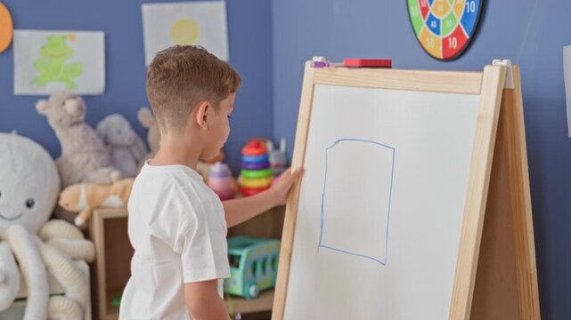 Boy drawing on whiteboard easel with marker, hand on board and drawing gesture inside building; concentration creativity.