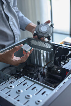 Computer engineer repair and assembling high-performance PC, CPU and cooler at workshop desk.