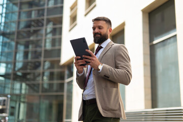 Fototapeta premium Bearded professional businessman using a tablet outdoors