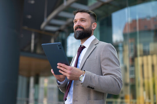 Businessman holding tablet looking forward in city