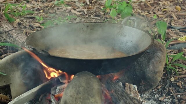 Traditional Beef Rendang Cooking in Wok Over Open Wood Fire in Rural Outdoor Kitchen