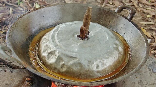 Simmering Traditional Beef Rendang in Aluminum Wok with Wooden-Handled Lid in Outdoor Kitchen