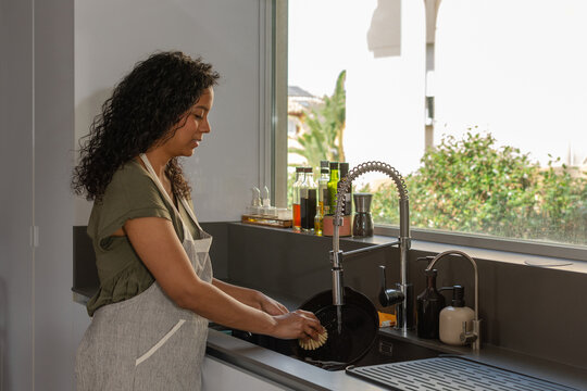 Hispanic woman practicing sustainable kitchen cleaning in modern home