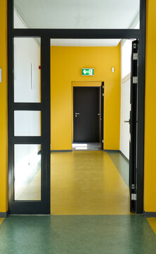 Open door leading into an empty yellow corridor of a public building