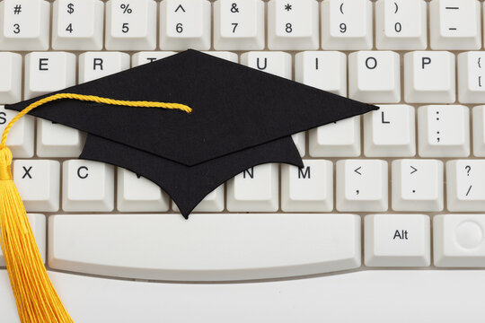 Grad cap on white computer keyboard for distance and e-learning