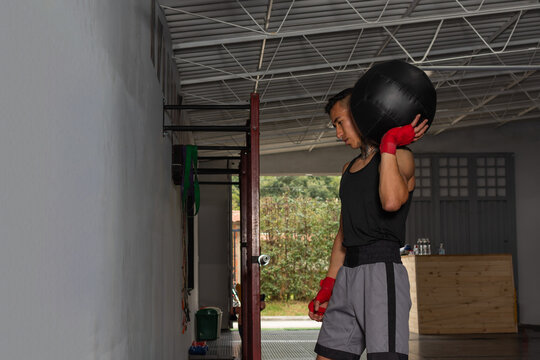 Young Hispanic boxer preparing medicine ball wall training in gym