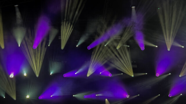 background with purple and white light beams and smoke at music event on stage