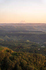 Naklejka premium Layers of green mountains and hills in the haze during sunset. Panoramic View of Green hills and Meadow.