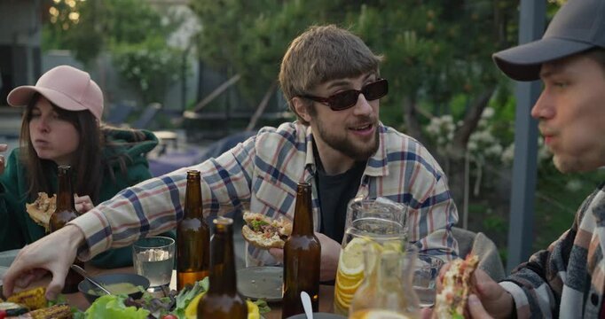 Friends sharing an outdoor meal at a garden table in soft daylight
