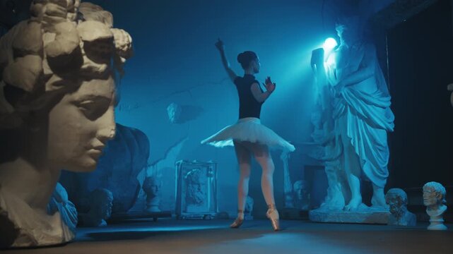 Talented and inspired ballerina dancing in darkness, rehearsal hall or museum. Beautiful slender female dancer performing classical choreography alone in dark room with ancient statues of Greek gods