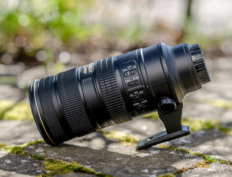Gothenburg, Sweden - April 21 2024: professional telephoto zoom lens lying on mossy stone surface in natural light.