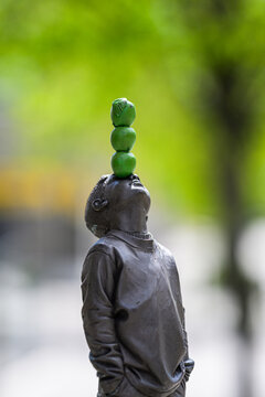 Varberg, Sweden - May 14 2026: Small gray statue balancing green spheres in shallow focus.