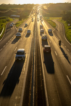 Marilia, SP, Brazil, November 19, 2025. Highway SP-294 in Marilia, at sunset. Intense traffic of cars and trucks flows through the green landscape, illuminated by the golden hour light.