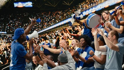 Energetic football fan with megaphone leading cheering supporters in stadium stands during intense soccer match, supporters in the fan zone cheering and creating powerful stadium noise. © DC Studio