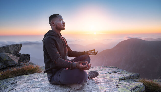 Male sitting in Meditation, crossed legs and yoga on a mountain summit above clouds at sunrise for zen peace
