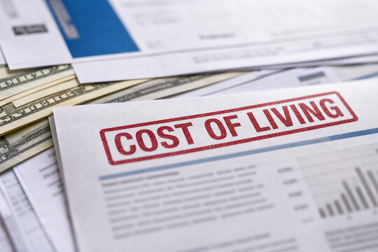 Close-up of financial paperwork and cash with a red cost of living stamp, illustrating expenses, inflation, budgeting, and economic pressure.
