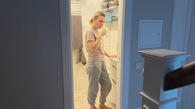 Woman brushing teeth in bathroom during evening routine. Everyday hygiene habit symbolizing health care, self discipline and preparation for sleep. Suitable for dental care, wellness and lifestyle
