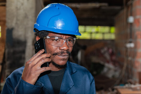 Worker talks on phone while wearing safety gear in a construction area