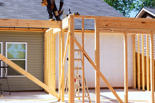 Workers are assembling wooden frame next to house with ladder during trusses frame