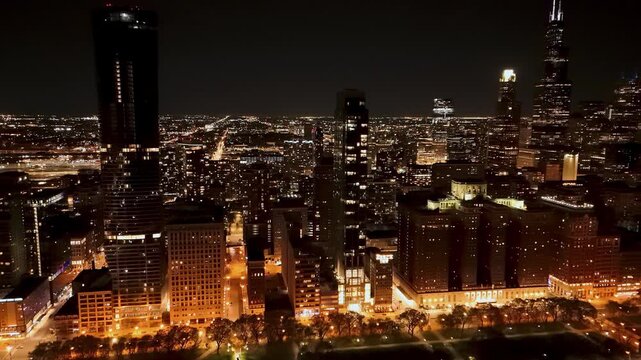 Stunning panoramic night view of the Chicago skyline featuring iconic skyscrapers like the Willis Tower and John Hancock Center illuminated against a dark sky with glowing city lights