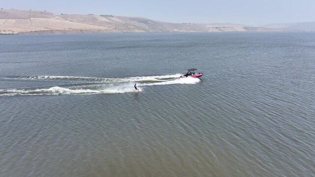 Beginner Learning to Water Ski Behind a Speedboat in a Scenic Mountain Landscape