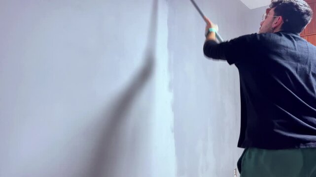 Professional painter renovating interior wall with paint roller