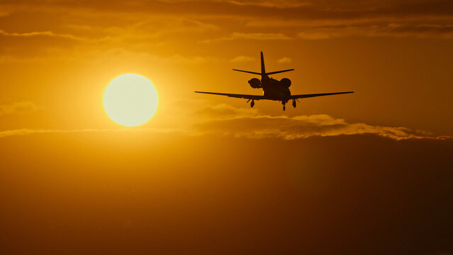 Silhouette of a small airplane flying against a vibrant sunset sky