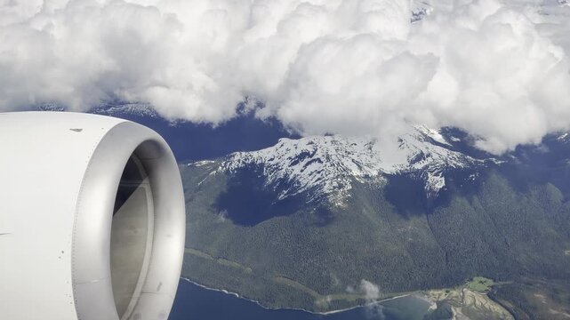 A jet engine cowling frames snowy peaks over a deep blue fjord delta