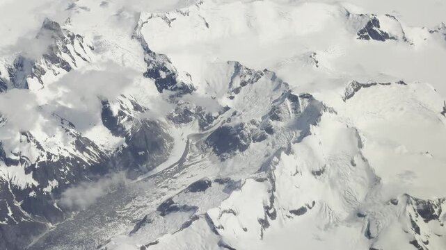 A moraine-banded glacier flows between jagged snowy summits