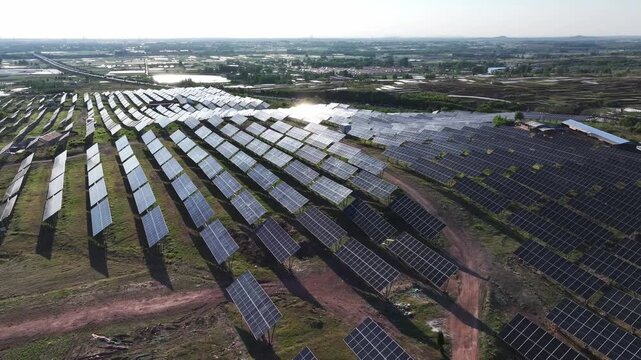 Aerial view of a large-scale photovoltaic power station with solar panels arranged in neat rows across rural fields