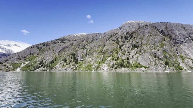 Sheer granite walls patched with green drop into still glacial water
