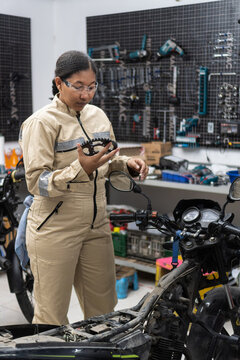 Female mechanic inspecting motorcycle gear in workshop