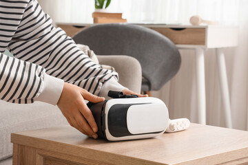 Fototapeta premium Person holding virtual reality headset on wooden table