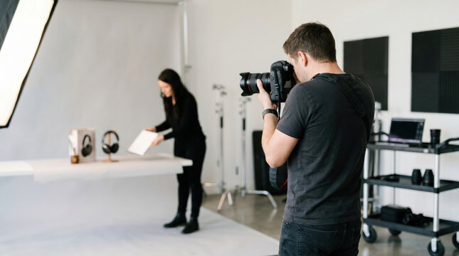 Professional photographer and female assistant capturing product images with assistant in studio