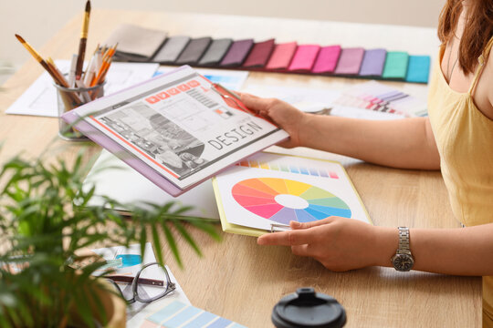 Person holding design and color wheel charts at creative workspace