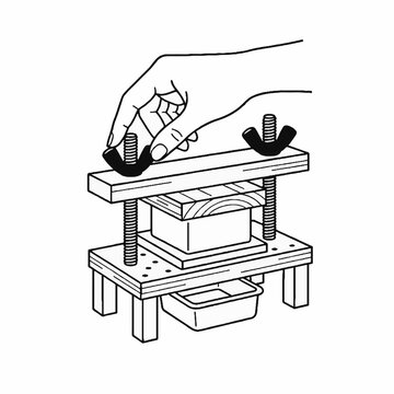 Hand adjusting a wooden tofu press machine for homemade cheese or curd making process.