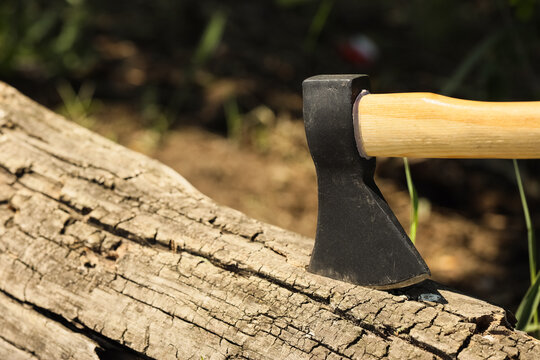 axe embedded in a log outdoors