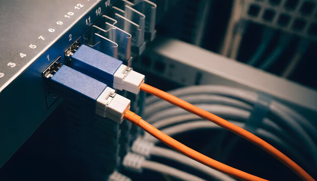 Closeup of fiber optic cables connected to a network switch in a server room, showing highspeed data transmission infrastructure and connectivity