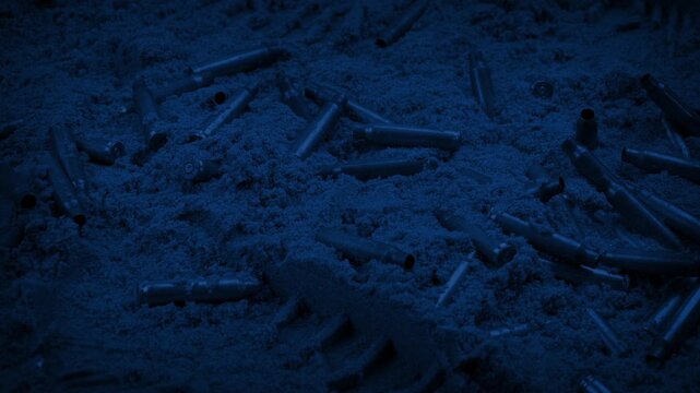 Bullets And Boot Prints In The Sand At Night

