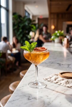 Elegant Amber Cocktail with Mint and Dried Orange Garnish on a Marble Bar Counter
