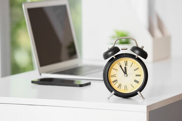 Naklejka premium Vintage alarm clock on desk with laptop and smartphone