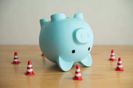 An upside-down piggy bank surrounded by traffic cones. Personal financial problem from high interest rate loan, loss investment, high expense, economy crisis, etc. effect to savings and so on concept.