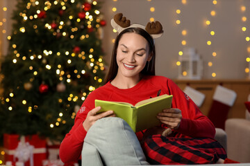 Naklejka premium Young girl reading book at home on Christmas eve