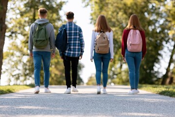 Obraz premium Students and teenagers walking with backpacks on a scenic park path at university