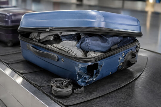 Damaged overpacked suitcase with broken wheel at airport baggage claim