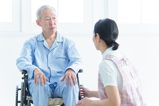 車椅子に乗った高齢者のサポートをする介護士
