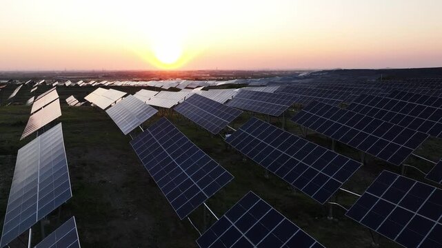 Large scale solar photovoltaic power station array at sunset with orderly panels across open fields